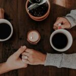 Couple holding hands and drinking coffee after effective relationship counselling,